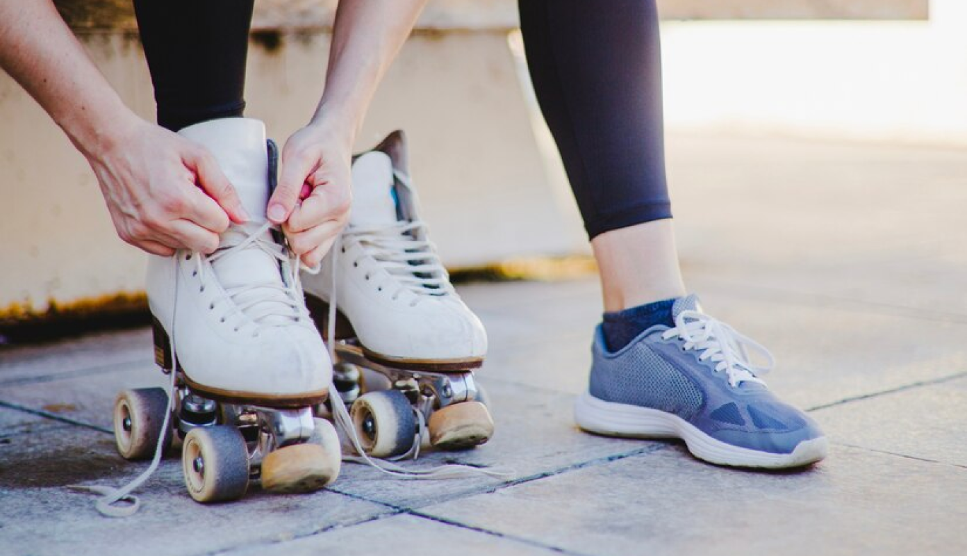 garota com patins numa quadra com uma das pernas para o alto