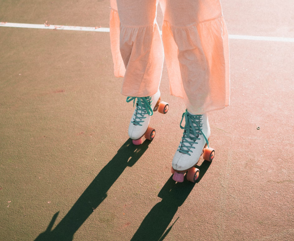 garota com patins numa quadra com uma das pernas para o alto